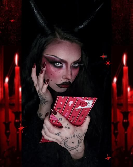Dramatic burgundy eyeshadow, extended black liner and deep red lips against a candlelit red backdrop.